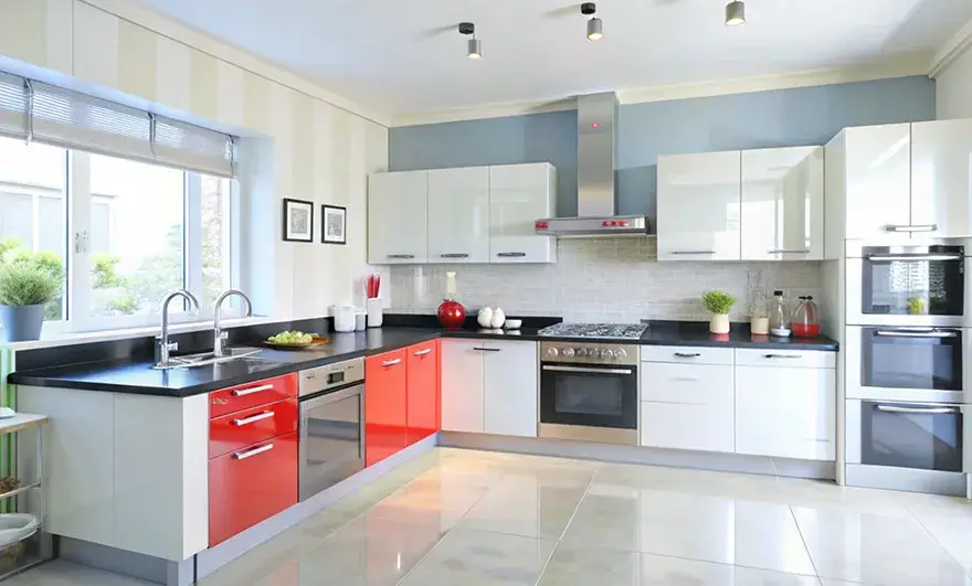 L-shaped modular kitchen design featuring crisp white cabinets with vibrant red accents and stainless steel appliances, creating a dynamic and modern cooking space.
